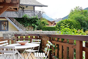 A balcony with a table and chairs and a bowl on it
