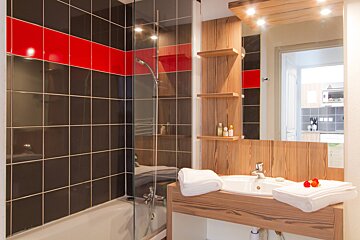 A bathroom with red and black tiles and a sink