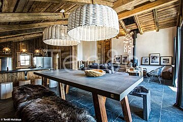 Rustic alpine chalet dining area featuring a large table with fur-draped benches and oversized woven pendant lights.