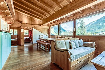 A living room with a couch and a table with mountains in the background