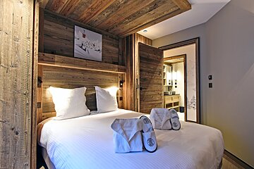 A bedroom with a wooden headboard and slippers on the bed