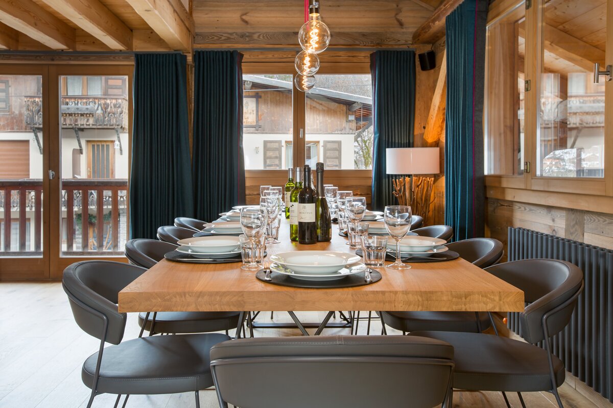 A bottle of wine sits on a wooden table in a dining room