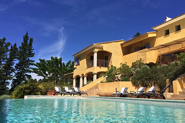A large yellow house with a swimming pool in front of it