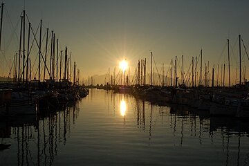 The sun is setting over a harbor full of boats