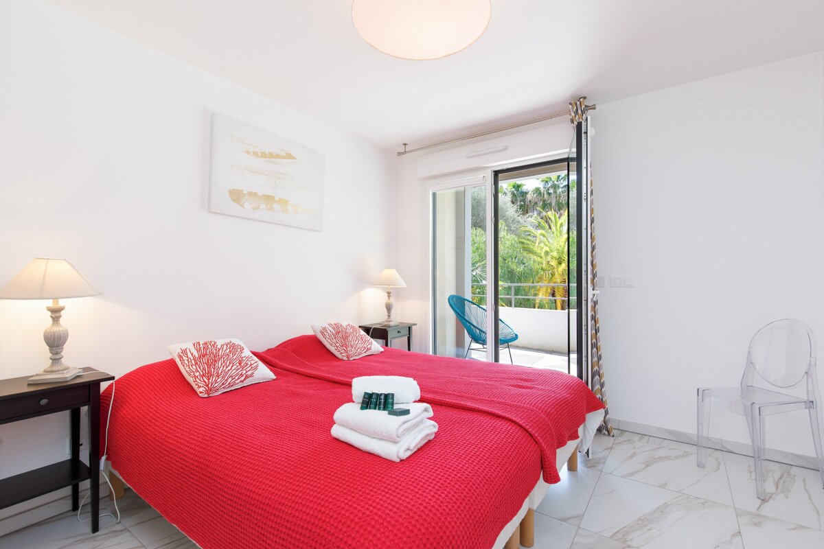 A bedroom with a red bed and a sliding glass door