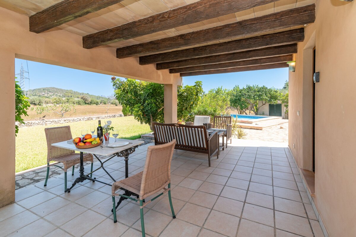 A patio with a table and chairs and a bottle of wine