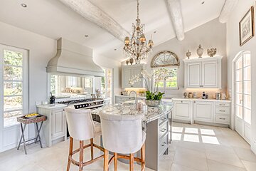 A kitchen with white cabinets and marble counter tops