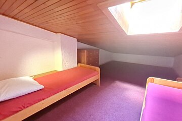 A bedroom with two beds and a skylight in the ceiling