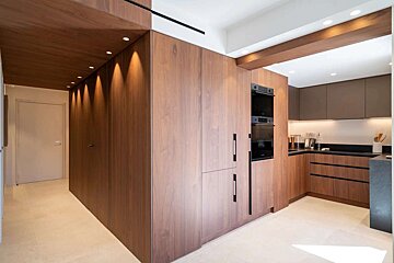 Modern kitchen featuring sleek wooden cabinetry, integrated appliances, and warm recessed lighting, creating a contemporary and inviting space.