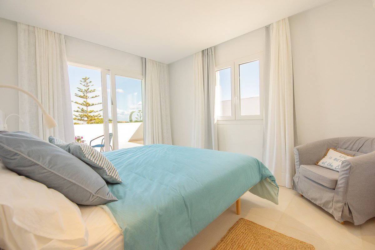 A bedroom with a bed and a chair with a pillow that says 