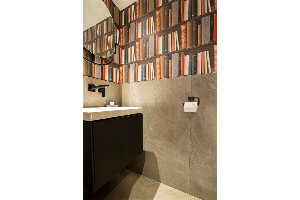 A bathroom with books on the wall and a sink