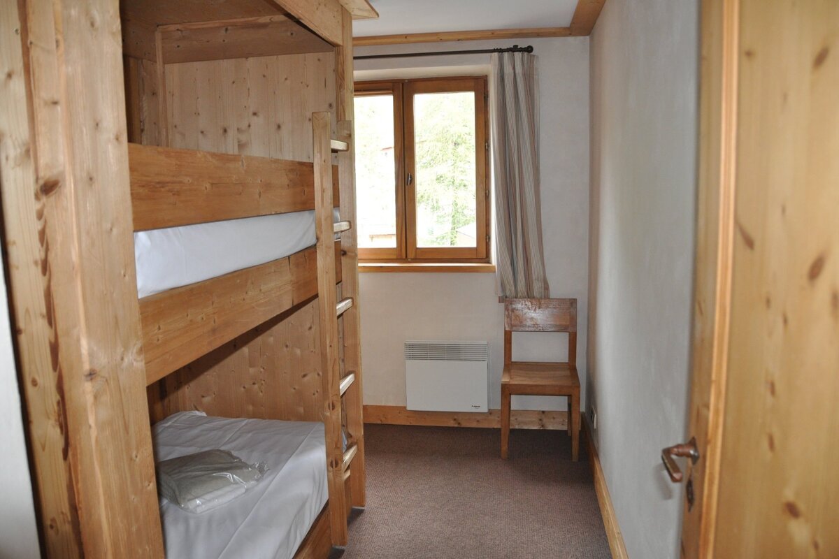 A small bedroom with bunk beds and a chair