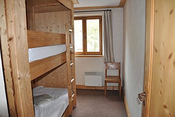 A small bedroom with bunk beds and a chair