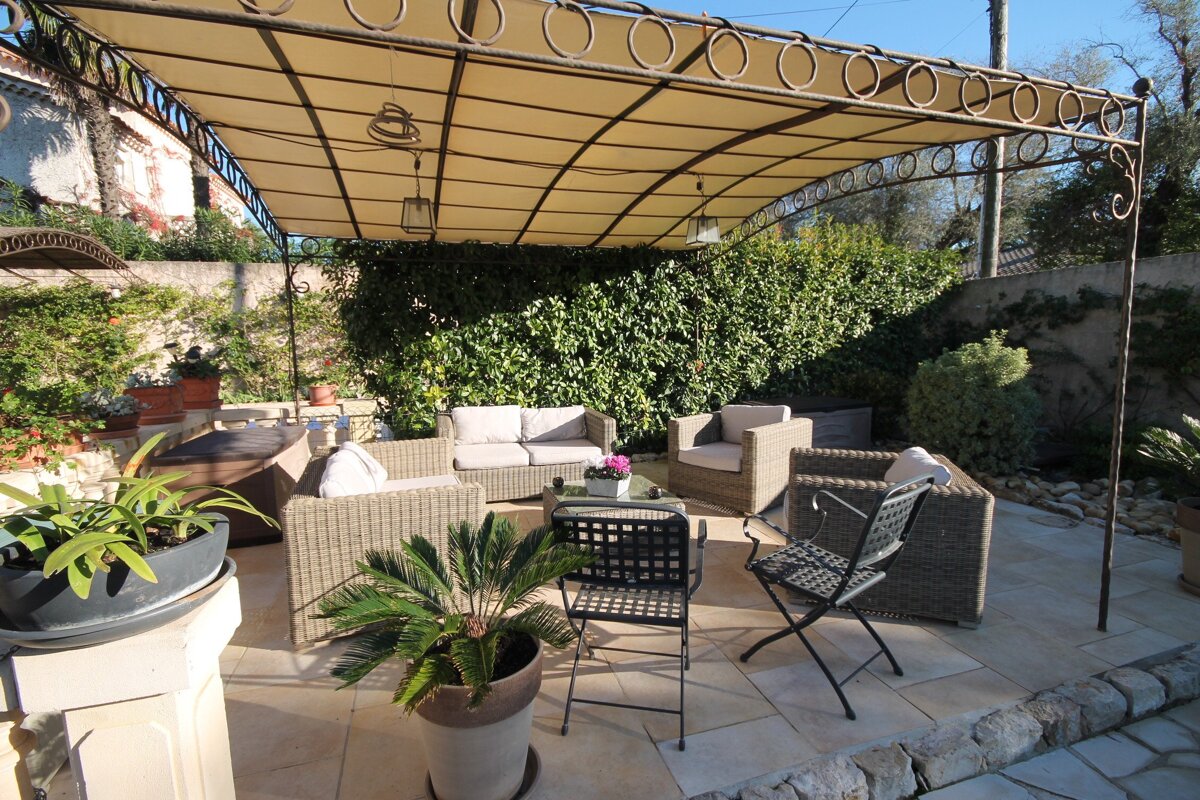 A patio with chairs and a couch under a canopy