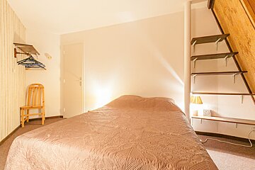 A small bedroom with a bed and a chair