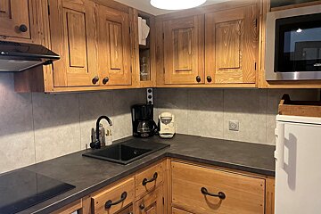 A kitchen with wooden cabinets and a stainless steel microwave