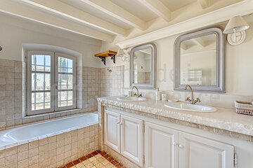 A bathroom with two sinks and two mirrors with the word de in the corner