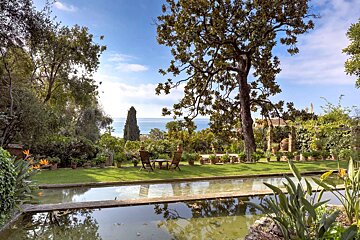 A pond in a garden with a view of the ocean