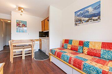 A living room with a colorful couch and a picture of mountains on the wall