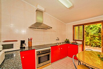 A kitchen with red cabinets and a stove top oven