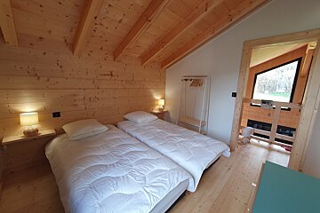 A wooden bedroom with two beds and a window