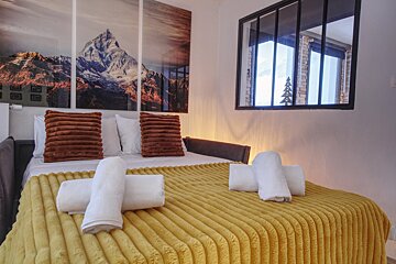 A bed with a yellow blanket and white towels on it