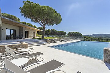 A large swimming pool is surrounded by chairs and tables