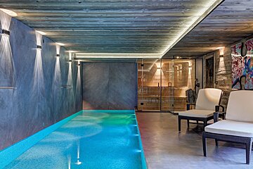 A swimming pool in a room with chairs and a sauna