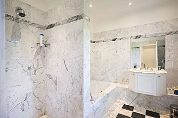 A bathroom with marble walls and a tub