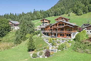 A large house sits in the middle of a lush green field