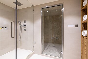 A bathroom with a walk in shower with a glass door