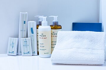 A bottle of nuxe creme de miel sits next to a towel