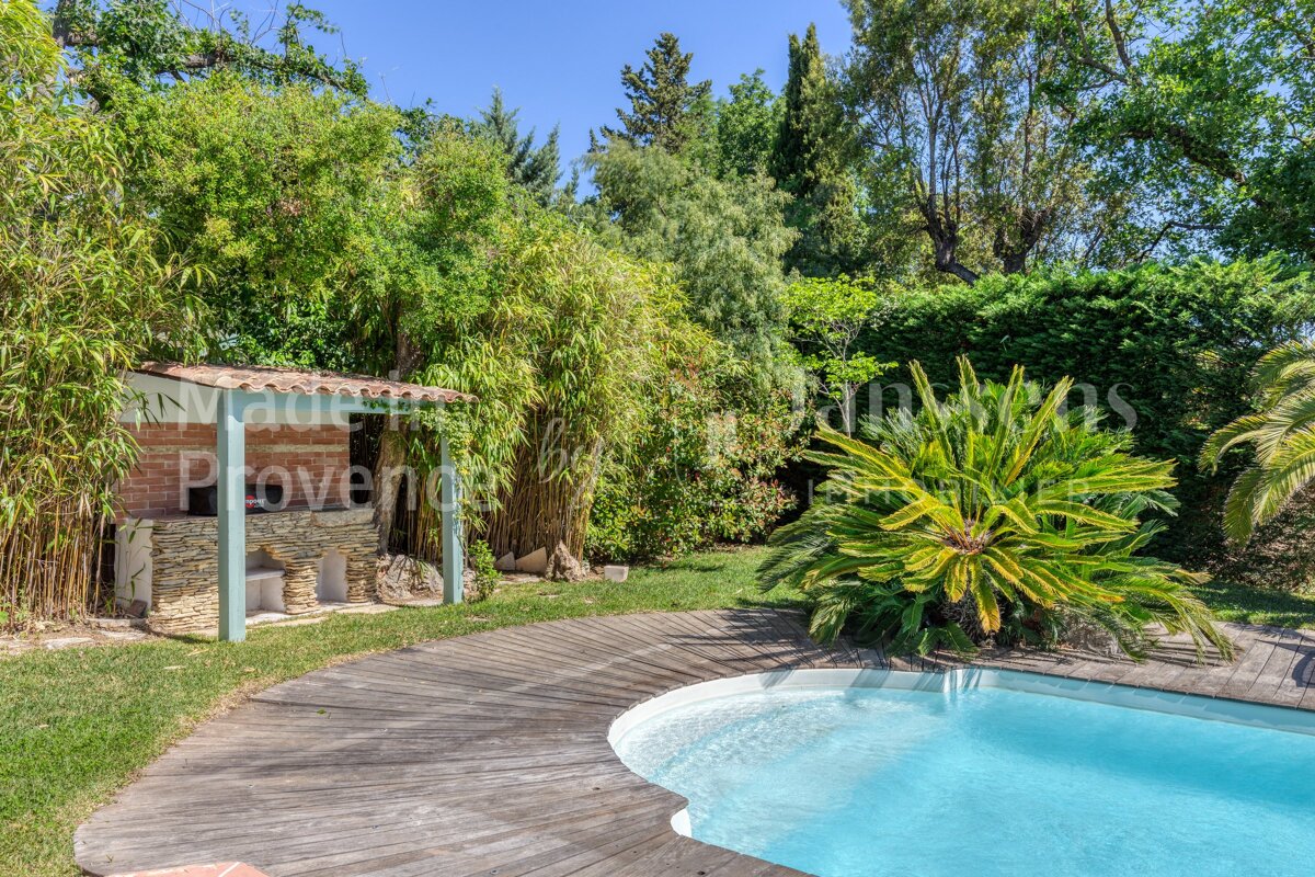 A swimming pool is surrounded by a wooden deck and a brick building that says provence