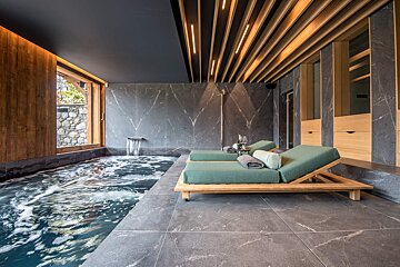A large indoor pool with two lounge chairs in front of it