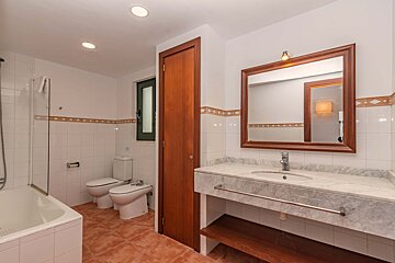 A bathroom with two toilets a sink and a mirror