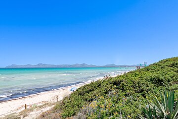 A beach with mountains in the background and a sign that says