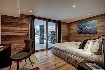 A bedroom with a painting on the wall above the bed