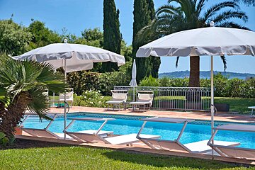 A swimming pool with chairs and umbrellas around it