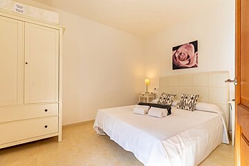A bedroom with a bed and a picture of a rose on the wall