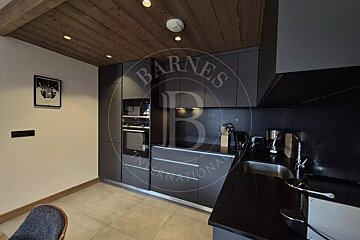 Modern kitchen featuring dark grey cabinets, black countertops, built-in appliances, tile floors, and a wood-paneled ceiling.