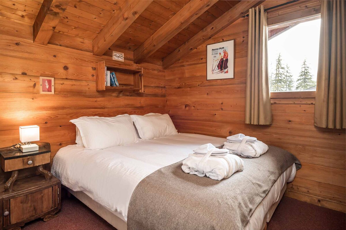 A bed in a wooden cabin with a poster on the wall that says