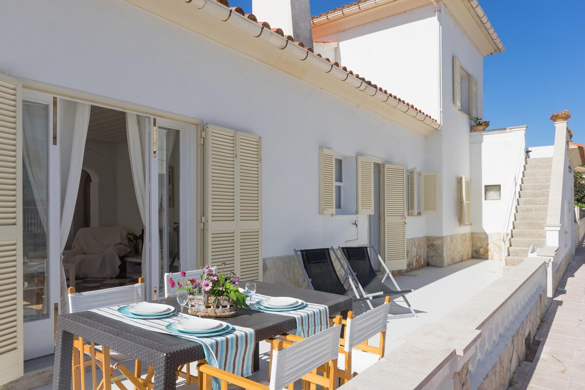 A patio with a table and chairs and plates on it