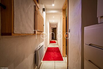 A long hallway with a red rug and the number 80 on the wall