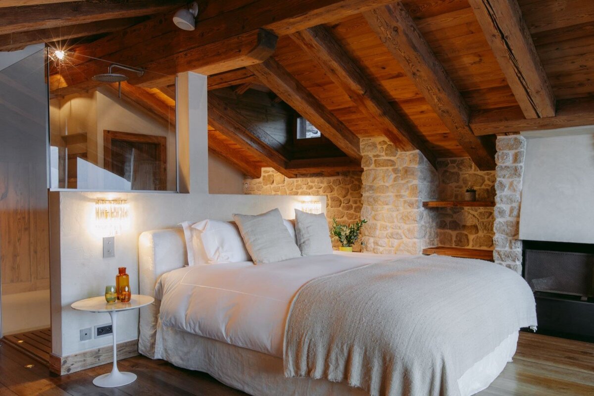 A bedroom with a large bed and a stone fireplace