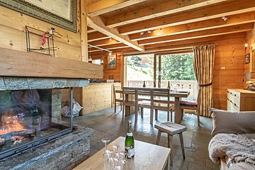A bottle of champagne sits on a table in front of a fireplace