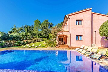 A pink house with a swimming pool in front of it