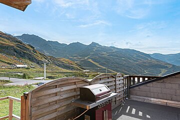 A coca cola grill sits on a balcony overlooking mountains