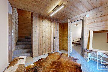 A room with a cowhide rug and stairs and a sign that says alpine-pro