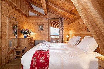 A wooden bedroom with a bed and dresser