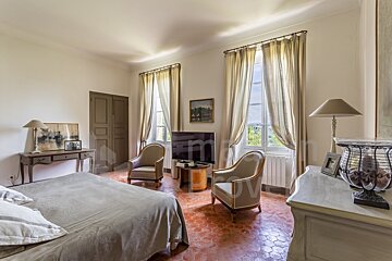 A bedroom with a large bed and chairs and a tv